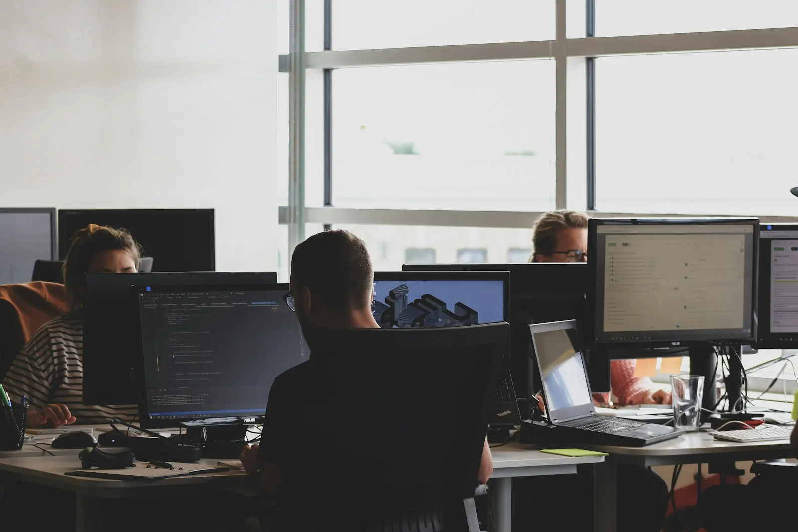 Engineers working at their desks with code on the monitors