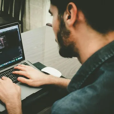 A developer typing on a laptop with code on the screen