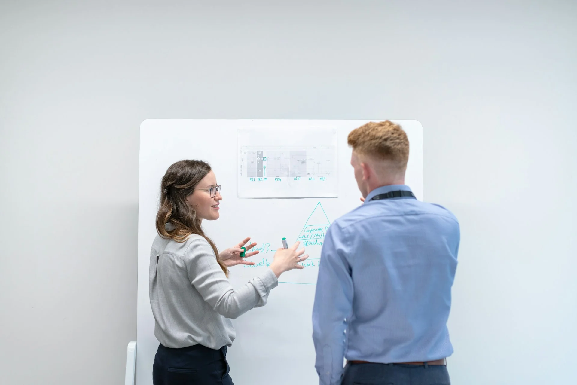 Two colleagues weighing options at a whiteboard in a bright office