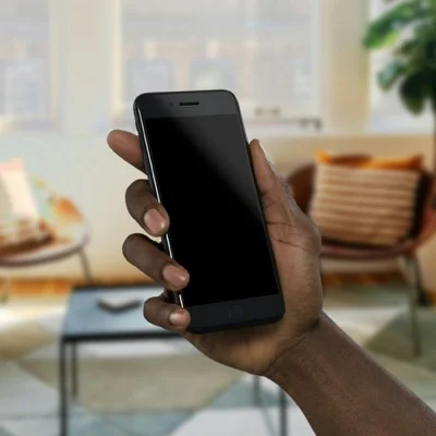 Una mà sosté un telèfon intel·ligent en una sala d'estar