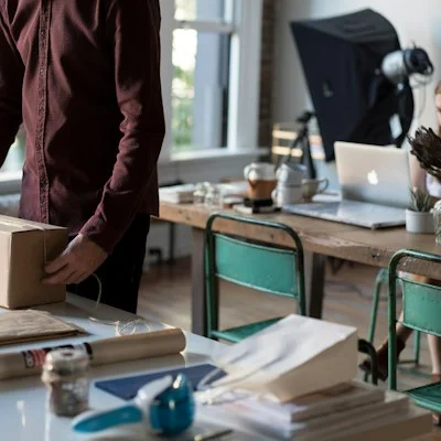 Una persona cerrando un paquete de cartón sobre una mesa: logística de e-commerce