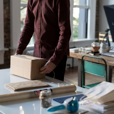 Una persona sostiene un paquete de cartón sobre una mesa: logística de e-commerce